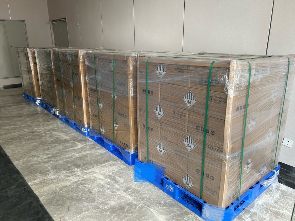 A row of SK On E777 battery cell pallets lined up on the ground, wrapped in protective film and awaiting container loading.