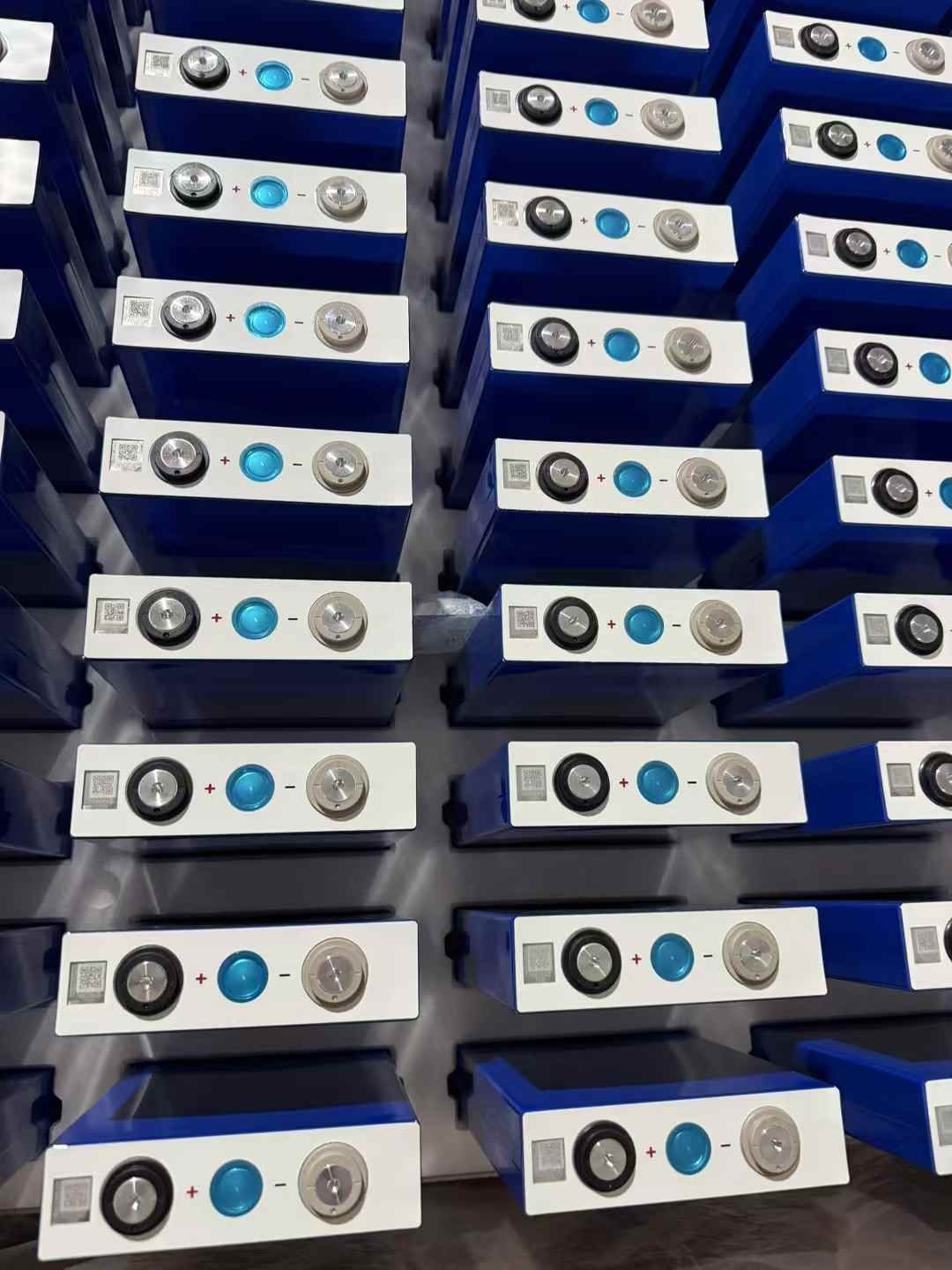 Bulk stock of EVE LF105 3.2V 105Ah LiFePO4 prismatic cells arranged on a pallet for wholesale shipment.