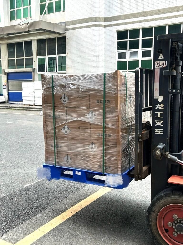 Forklift loading pallets of SK On E777 lithium-ion battery cells with UN3480 labels into a shipping container.